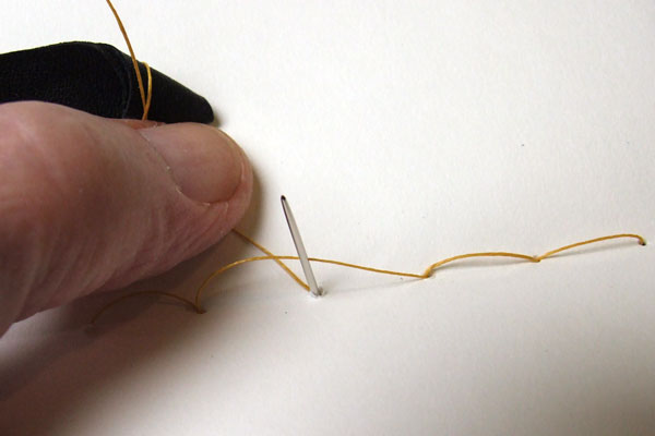 First thread and needle must pass on opposite sides of thread loop